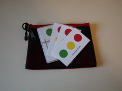A set of palm-sized cards with red, yellow, and green circles arranged like a stop light on each, placed inside an open mesh envelope with a pair of scissors on the side.