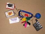 A keychain debrief with various items attached, including a mini deck of playing cards, plastic body part models, and other activity tools.