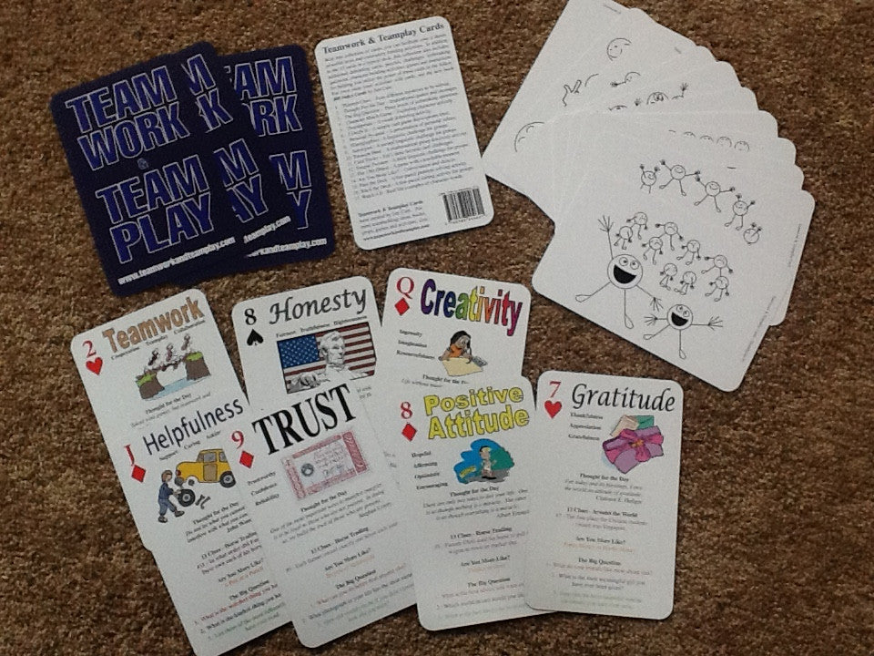 A collection of cards laid out on a surface, with various illustrations and text on them, designed for team and community building activities.