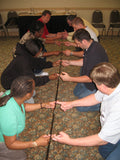 A collapsible tent pole held horizontally by a team, each person supporting it with an extended index finger.